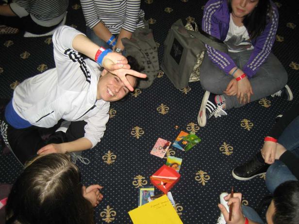 Eine Gruppe junger Leute sitzt auf dem Boden und spielt ein Kartenspiel.