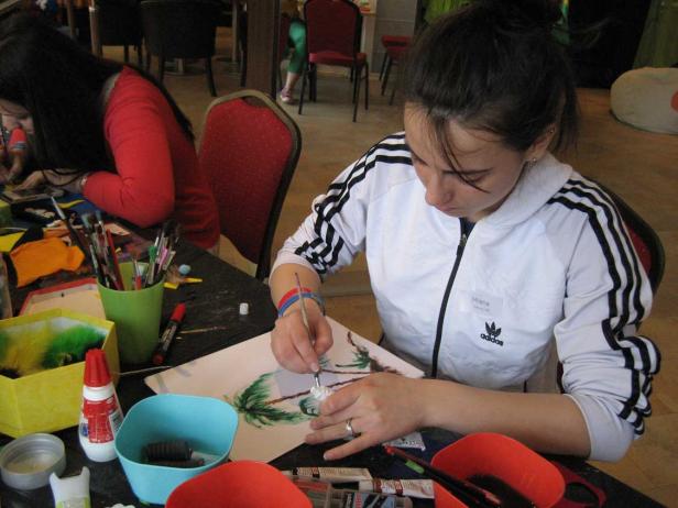 Eine junge Frau namens Milena malt ein Bild mit Palmen.