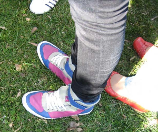 Mehrere Personen stehen auf einer Wiese, jede mit unterschiedlichen Schuhen.