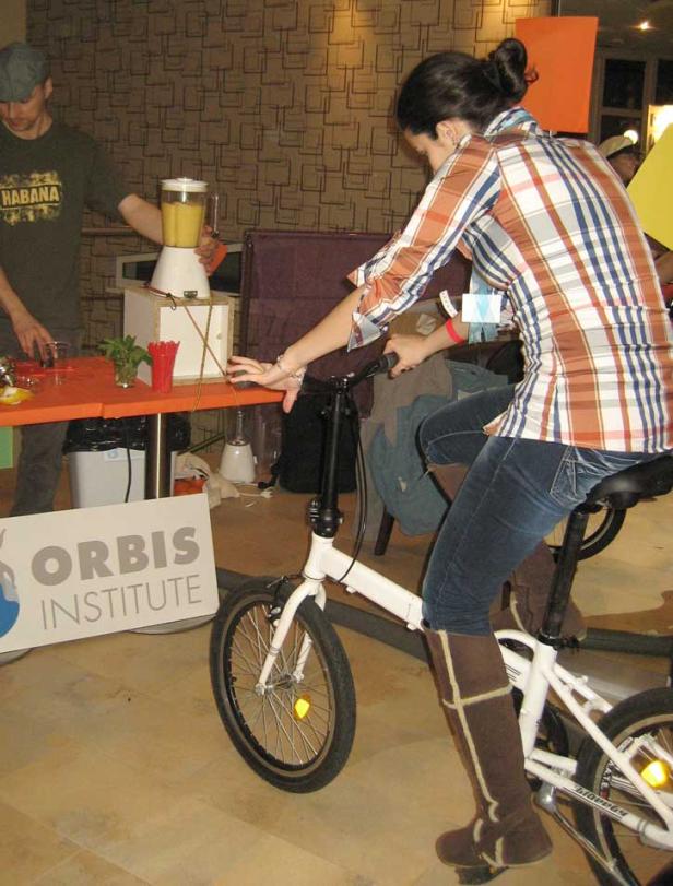 Eine Frau sitzt auf einem Fahrrad, um einen Smoothie für das Orbis Institute zu mixen.