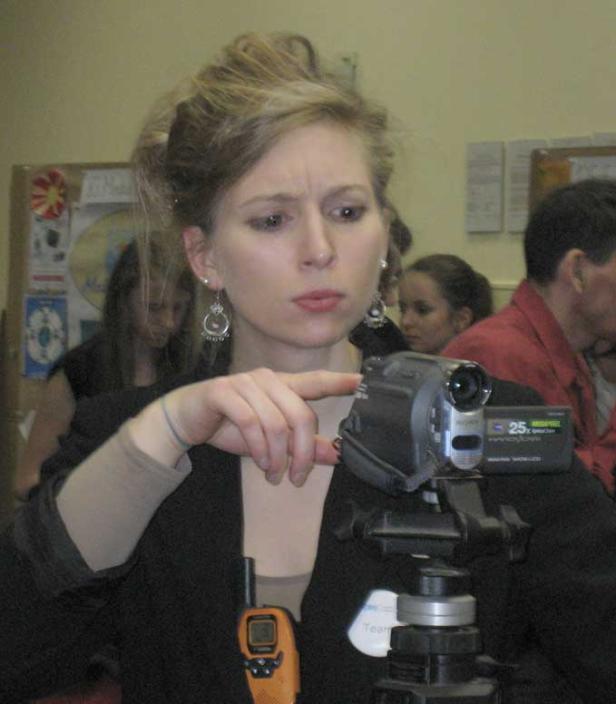 Eine Frau bedient eine Videokamera auf einem Stativ.