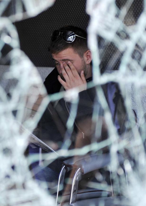 BRITAIN LONDON RIOTS Ein Mann sitzt hinter einer zerbrochenen Scheibe und bedeckt sein Gesicht mit der Hand.