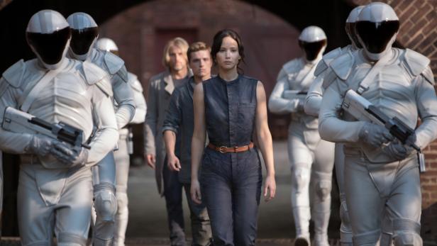 Jennifer Lawrence, Josh Hutcherson und Liam Hemsworth umgeben von Soldaten in „Die Tribute von Panem – Mockingjay Teil 2“.