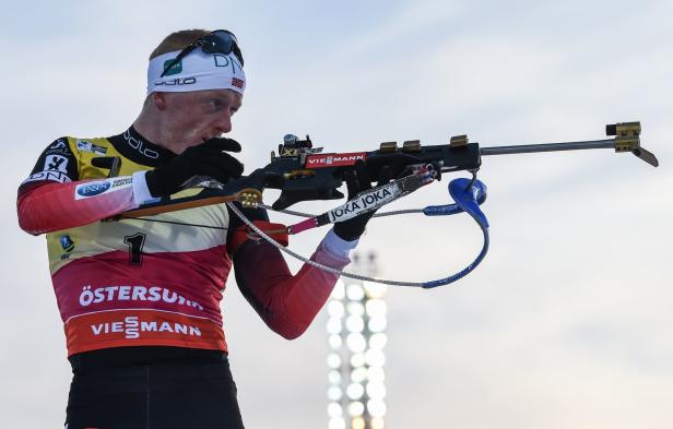 Ein Biathlet zielt mit seinem Gewehr auf ein Ziel.