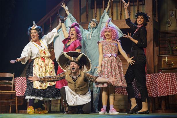 Dinosaurier, Das Musical Eine Gruppe von Schauspielerinnen und Schauspielern in bunten Kostümen auf einer Theaterbühne.