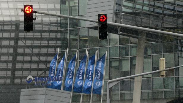 Bei Schneefall zeigen Ampeln rote Pfeile vor einem Bürogebäude der Hypo Group Alpe Adria.