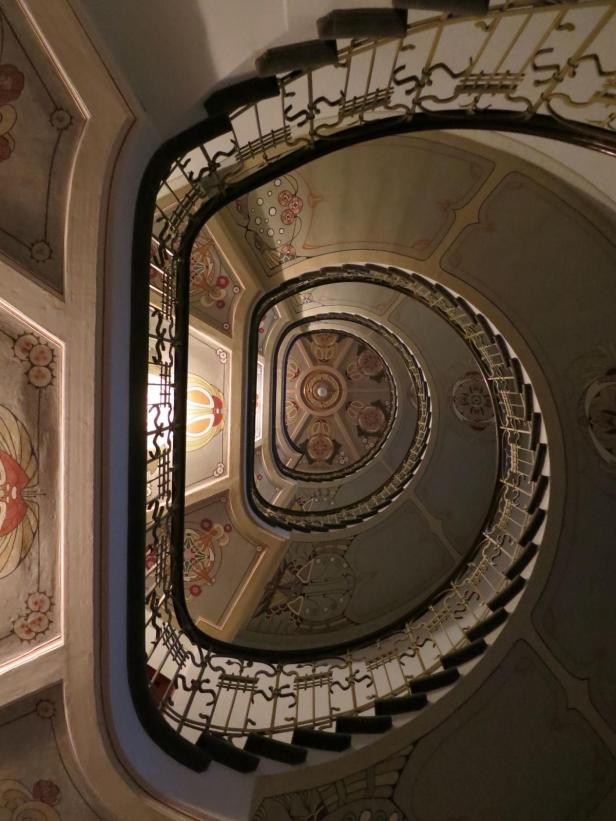 Ein Blick von unten auf ein kunstvoll verziertes Wendeltreppenhaus.