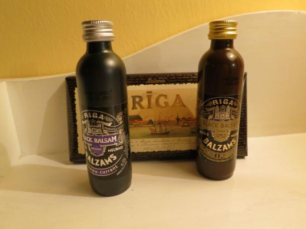 Zwei Flaschen Riga Black Balsam stehen vor einer Riga-Schokoladenverpackung.