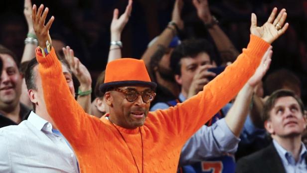 Spike Lee mit orangefarbenem Hut und Pullover feuert sein Team an.