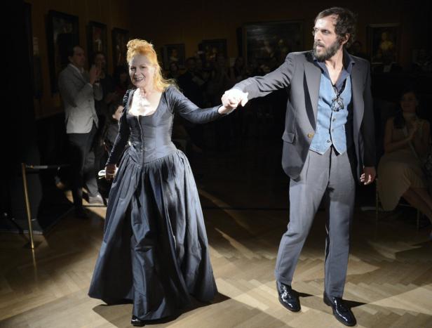 Vivienne Westwood und Andreas Kronthaler nehmen auf einer Bühne Händchen.
