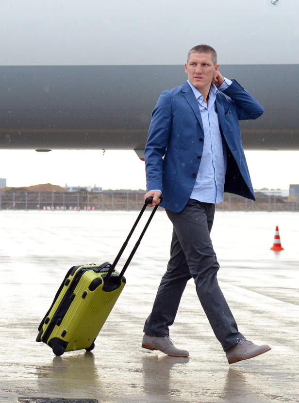 Bastian Schweinsteiger geht mit einem gelben Koffer über das Rollfeld.