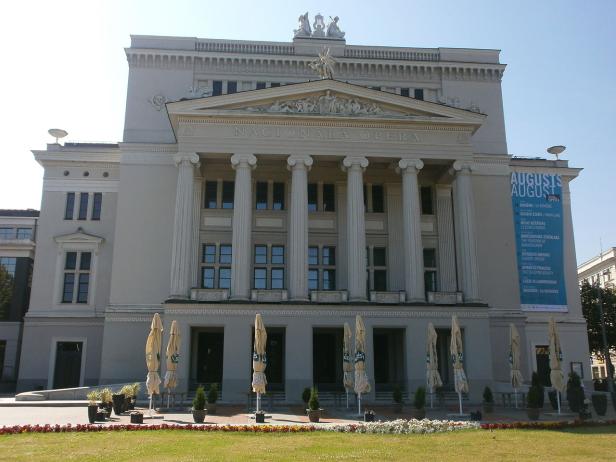 Die Fassade der Lettischen Nationaloper in Riga mit einem Veranstaltungsplakat.