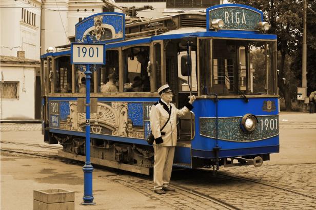 Ein Schaffner steht vor einer blauen Retro-Straßenbahn aus dem Jahr 1901 in Riga.