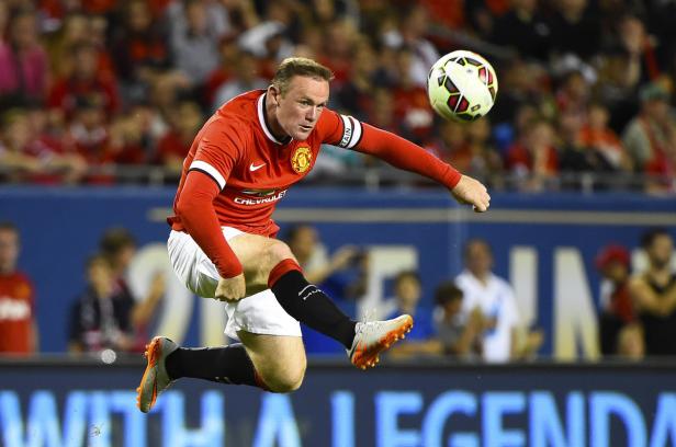 Wayne Rooney springt, um einen Fußball zu treten.