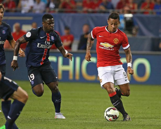 Ein Fußballspieler im roten Trikot von Manchester United dribbelt den Ball, verfolgt von einem Spieler von Paris Saint-Germain.