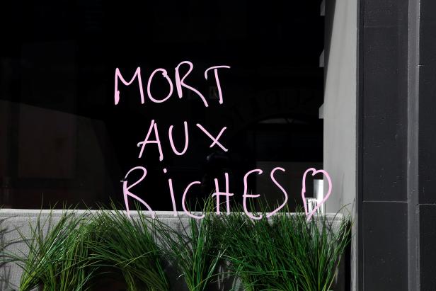 Graffiti reads "Death to the rich" near a burnt Tarneaud Bank near the Champs-Elysees avenue, during clashes with riot police forces during a demonstration by the "yellow vests" movement in Paris