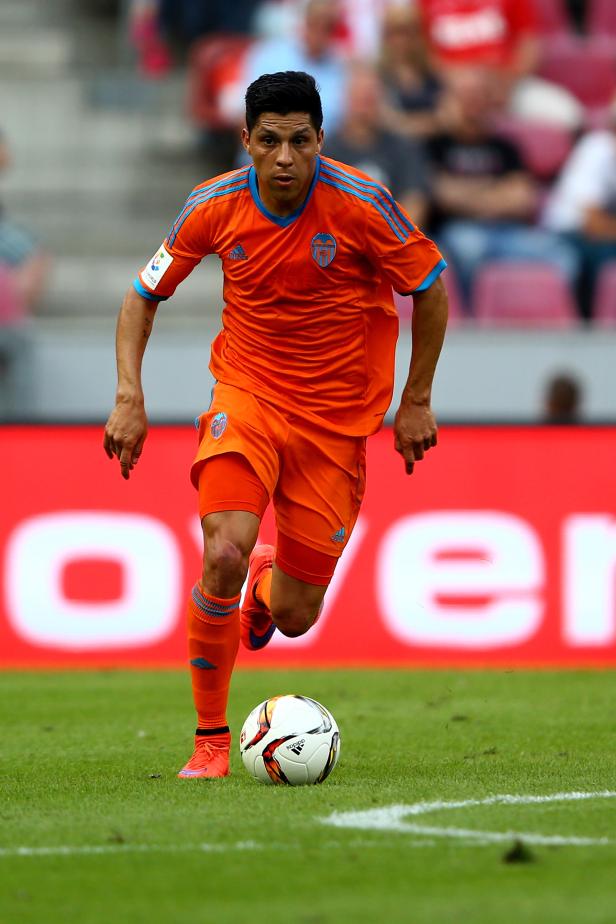 Ein Fußballspieler in orangefarbener Sportkleidung dribbelt den Ball.