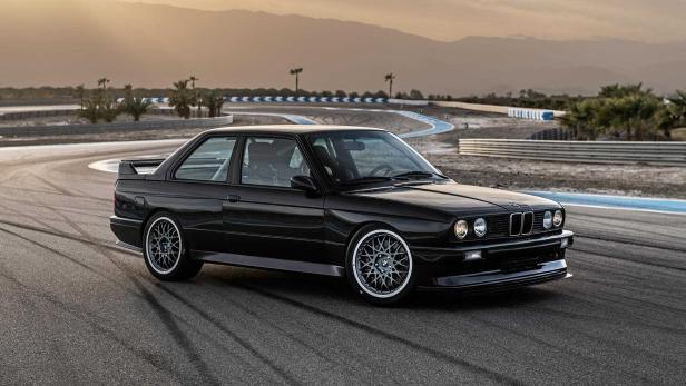 Ein schwarzer BMW E30 steht auf einer Rennstrecke.