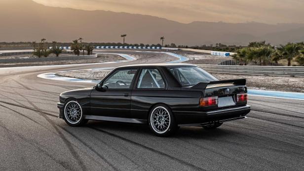 Ein schwarzer BMW E30 steht auf einer Rennstrecke.