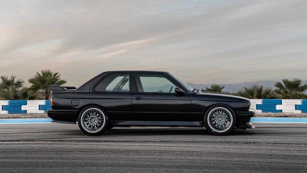 Ein schwarzer BMW E30 steht auf einer Rennstrecke.