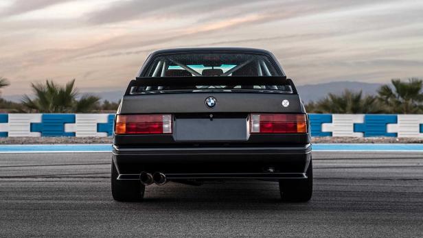 Die Rückansicht eines schwarzen BMW E30 auf einer Rennstrecke.