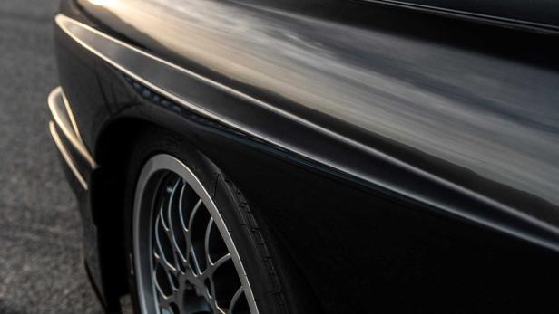 Detailaufnahme eines schwarzen Autos mit silberner Felge.