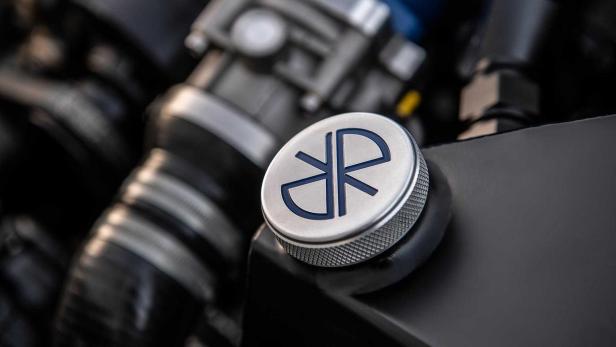 Ein silberner Deckel mit einem blauen Logo befindet sich auf einem Motor.