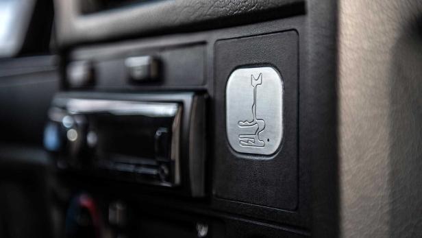 Das Interieur eines Autos mit einem Schalthebel-Symbol auf einer Metallplakette.