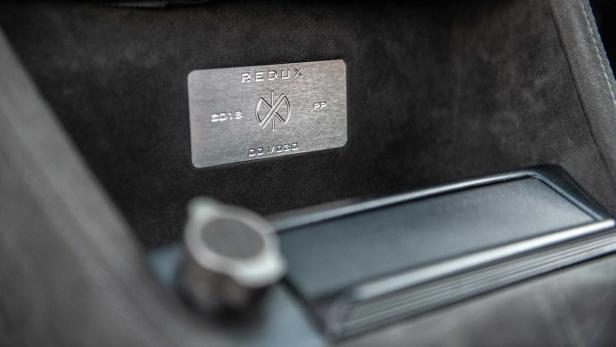 Eine Plakette mit der Aufschrift „Redux 2018 001/030“ im Innenraum eines Fahrzeugs.