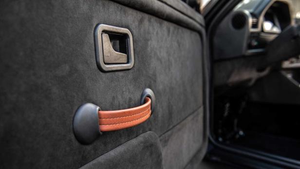 Detailansicht einer Autotür mit Griff und Fensterkurbel.