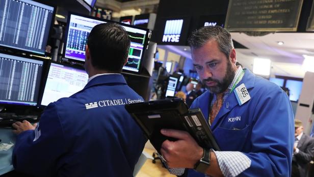 Zwei Börsenmakler arbeiten an ihren Computern und Tablets an der New Yorker Börse.