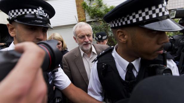 Jeremy Corbyn wird von Polizisten und Fotografen umringt.