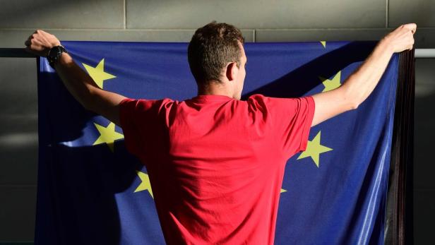 Ein Mann hält die Europaflagge hoch.