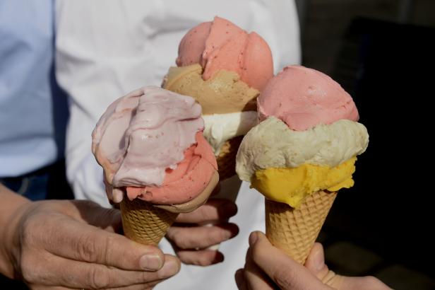 Drei Hände halten Eiswaffeln mit verschiedenen Eissorten.