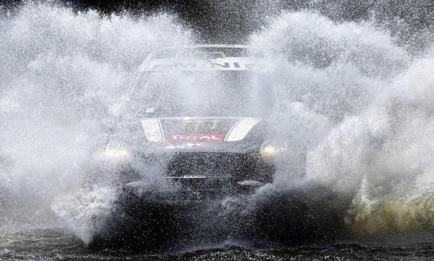 Ein Mini Cooper durchfährt eine Wasserfontäne während eines Rennens.