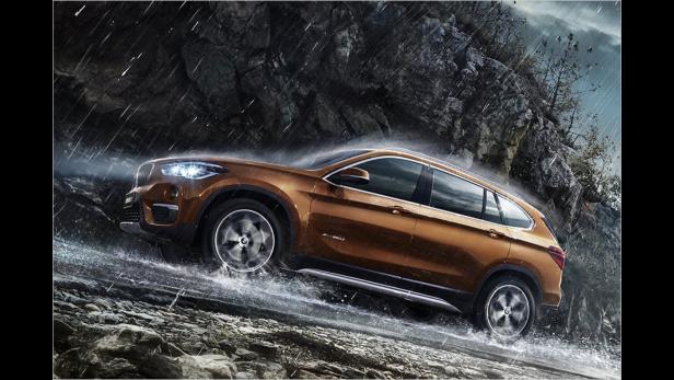 Ein goldfarbener BMW X1 fährt im Regen über eine steinige Straße.