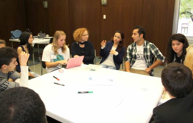 Eine Gruppe junger Leute sitzt an einem Tisch und diskutiert.