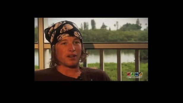 Ein Mann mit einem Totenkopf-Bandana spricht vor einem Fenster.