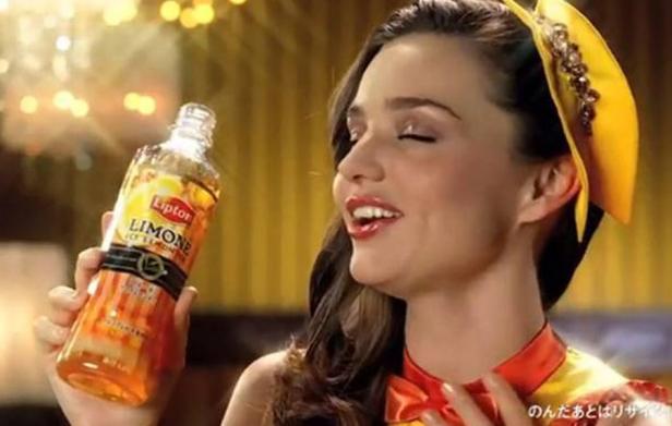 Eine Frau hält eine Flasche Lipton Ice Tea Limone in der Hand.