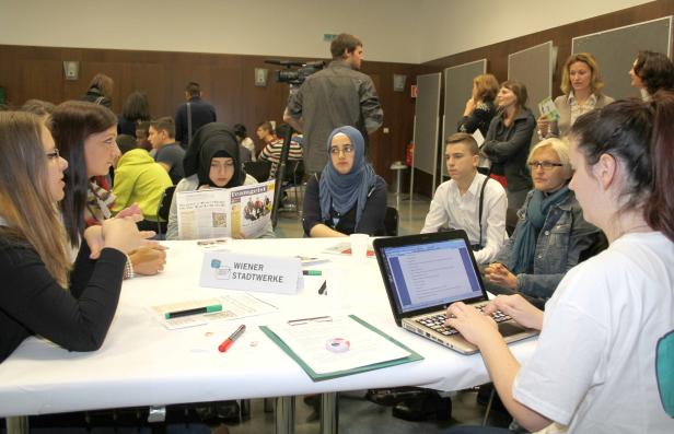 Eine Gruppe junger Menschen sitzt an einem Tisch der Wiener Stadtwerke.