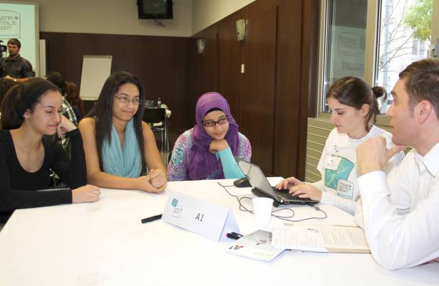 Eine Gruppe junger Leute sitzt an einem Tisch und arbeitet zusammen.