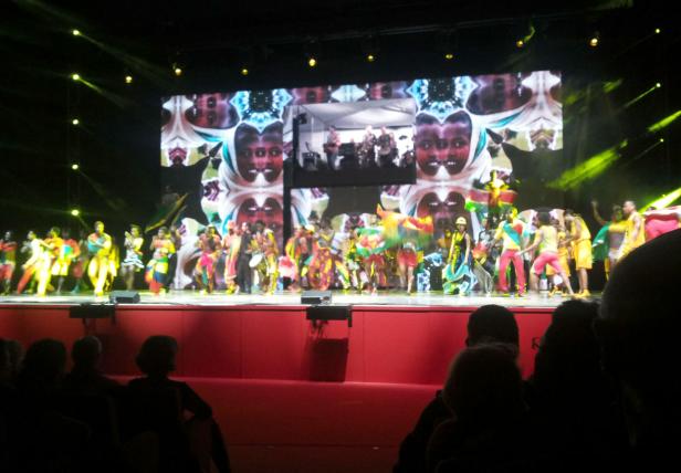 Eine Gruppe von Tänzern tritt in farbenfrohen Kostümen auf einer Bühne auf.