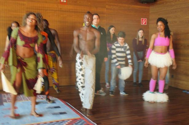 Eine Gruppe von Tänzern in farbenfrohen Kostümen führt eine Performance auf.