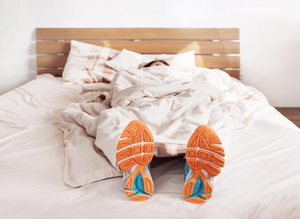 A woman lies with training shoes in the bet.