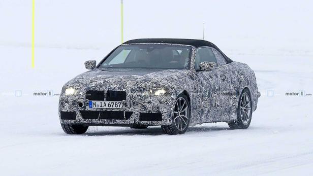 Ein getarntes BMW 4er Cabrio fährt auf einer schneebedeckten Straße.