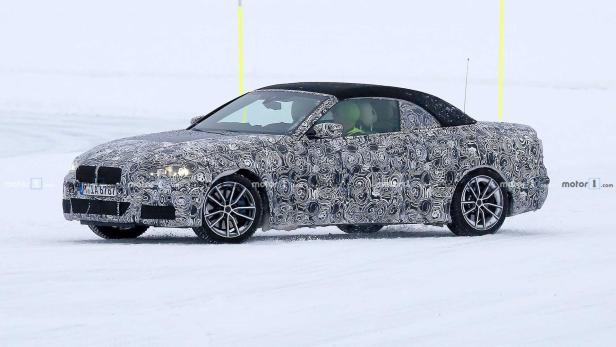 Ein Prototyp eines BMW-Cabrios mit Tarnmuster fährt auf einer schneebedeckten Straße.