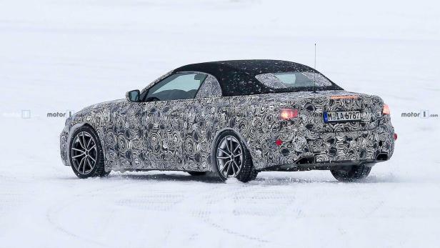 Ein getarntes Cabriolet fährt auf einer schneebedeckten Fläche.
