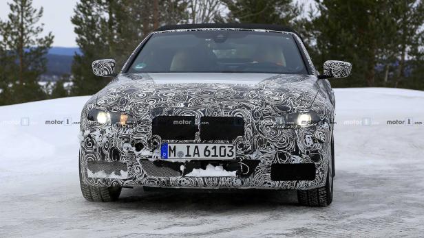 Ein Prototyp eines BMW-Cabrios mit Tarnmuster auf einer verschneiten Straße.