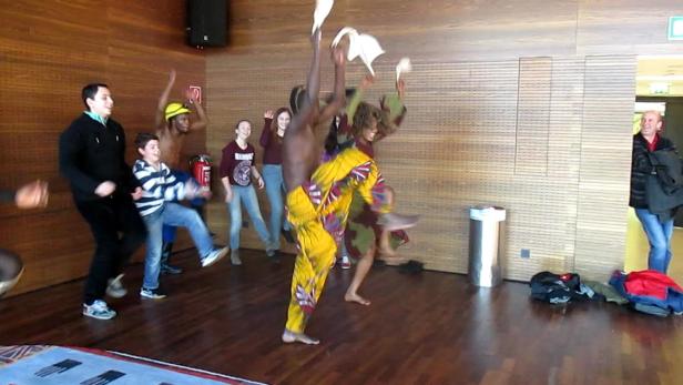 Eine Gruppe von Menschen tanzt in einem Raum mit Holzwänden.