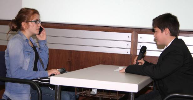 Ein Mädchen telefoniert, während ein Junge ein Mikrofon hält.